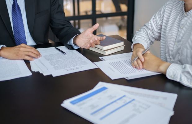 Two business professionals seated at a table, reviewing documents and discussing strategies.