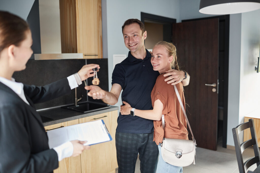Estate agent handing house keys to a happy couple