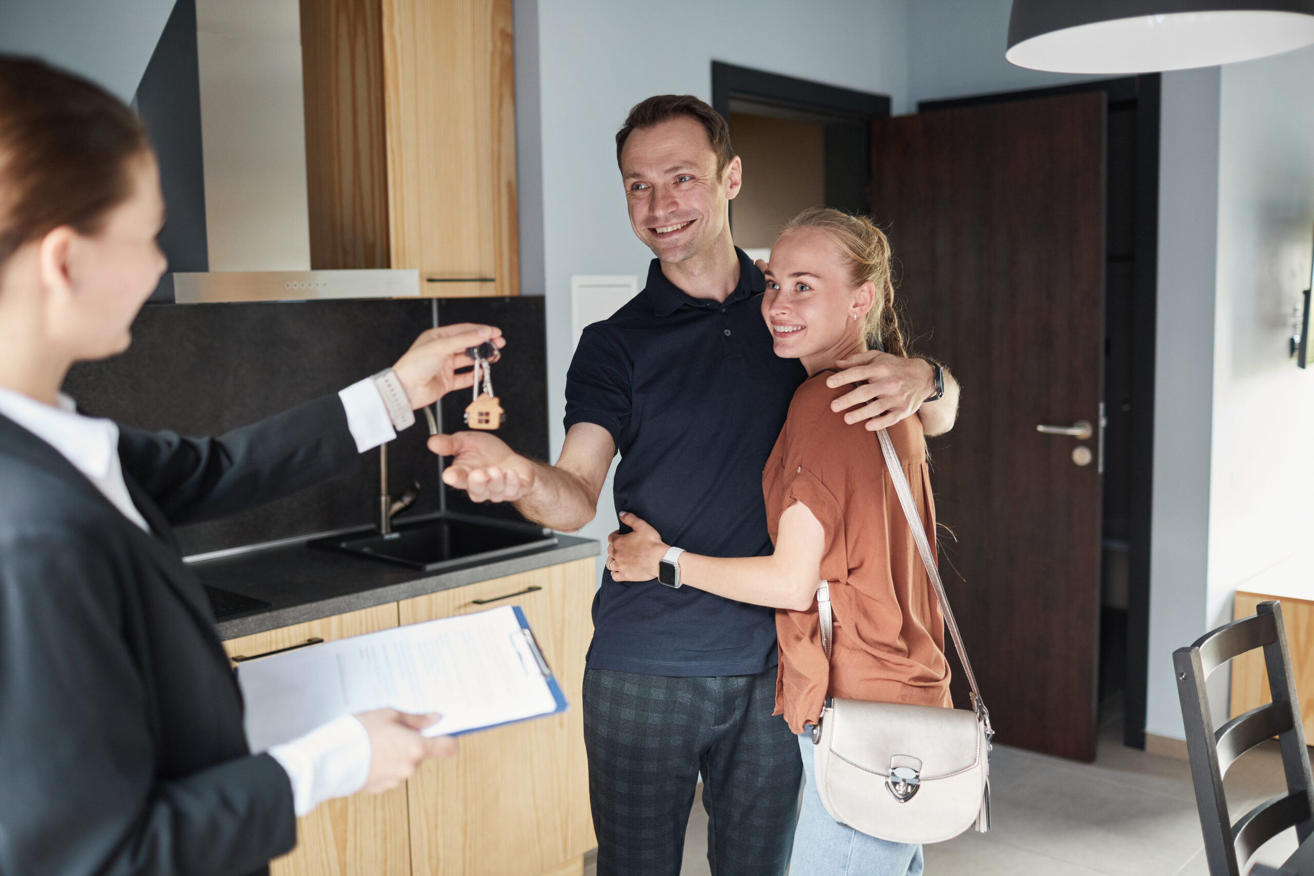 Estate agent handing house keys to a happy couple