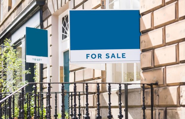 A For Sale sign is prominently displayed on the exterior of a building, indicating it is available for purchase.